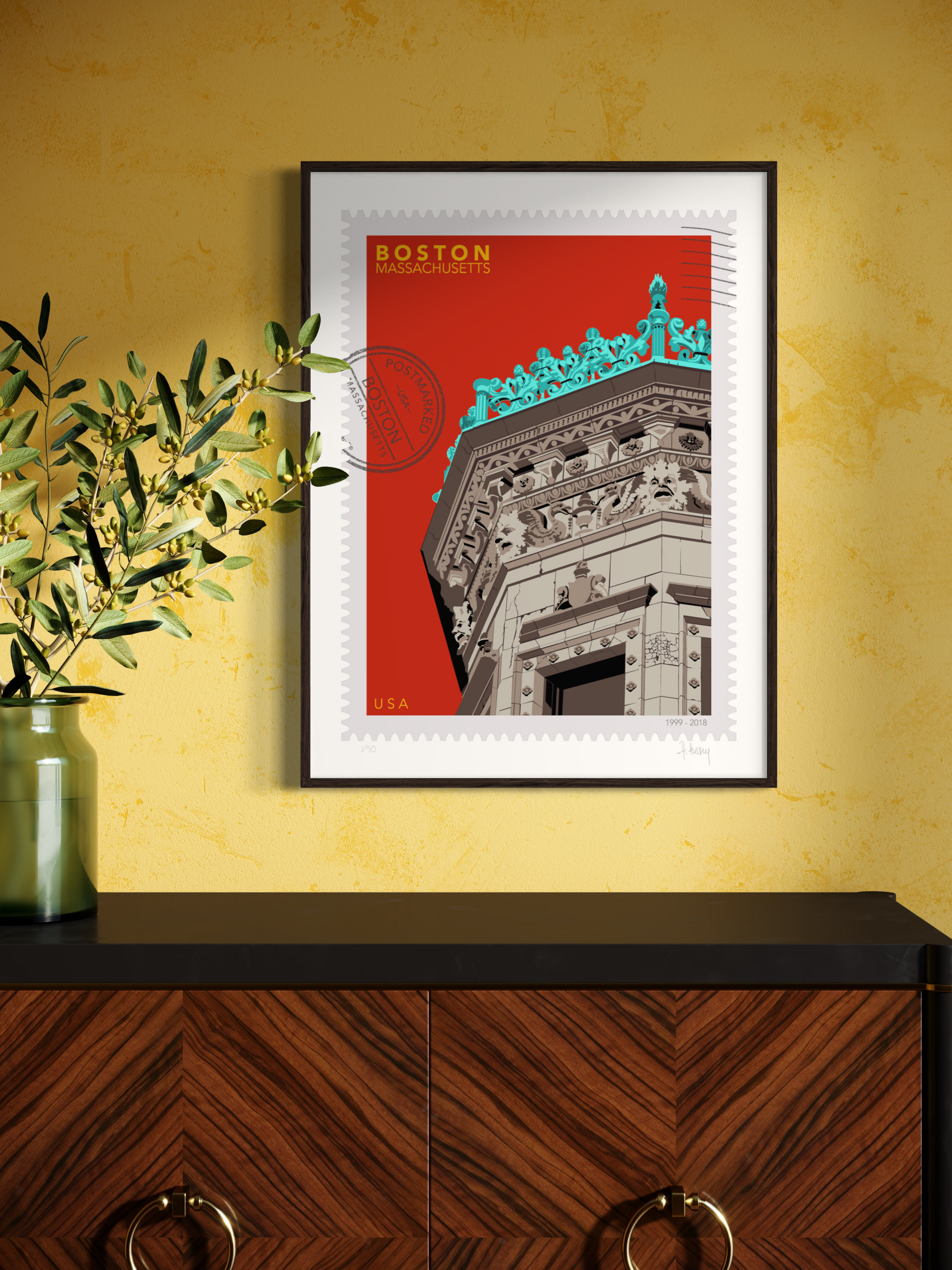 Drawing of the Proctor Building crowned with decorative elements on a red background, featuring the text 'Boston, Massachusetts' and 'USA'. Large postage stamp art, postmarked with D ART Studio stamp. Ana Hussey art. Framed on a yellow wall with a wooden cabinet and a plant.
