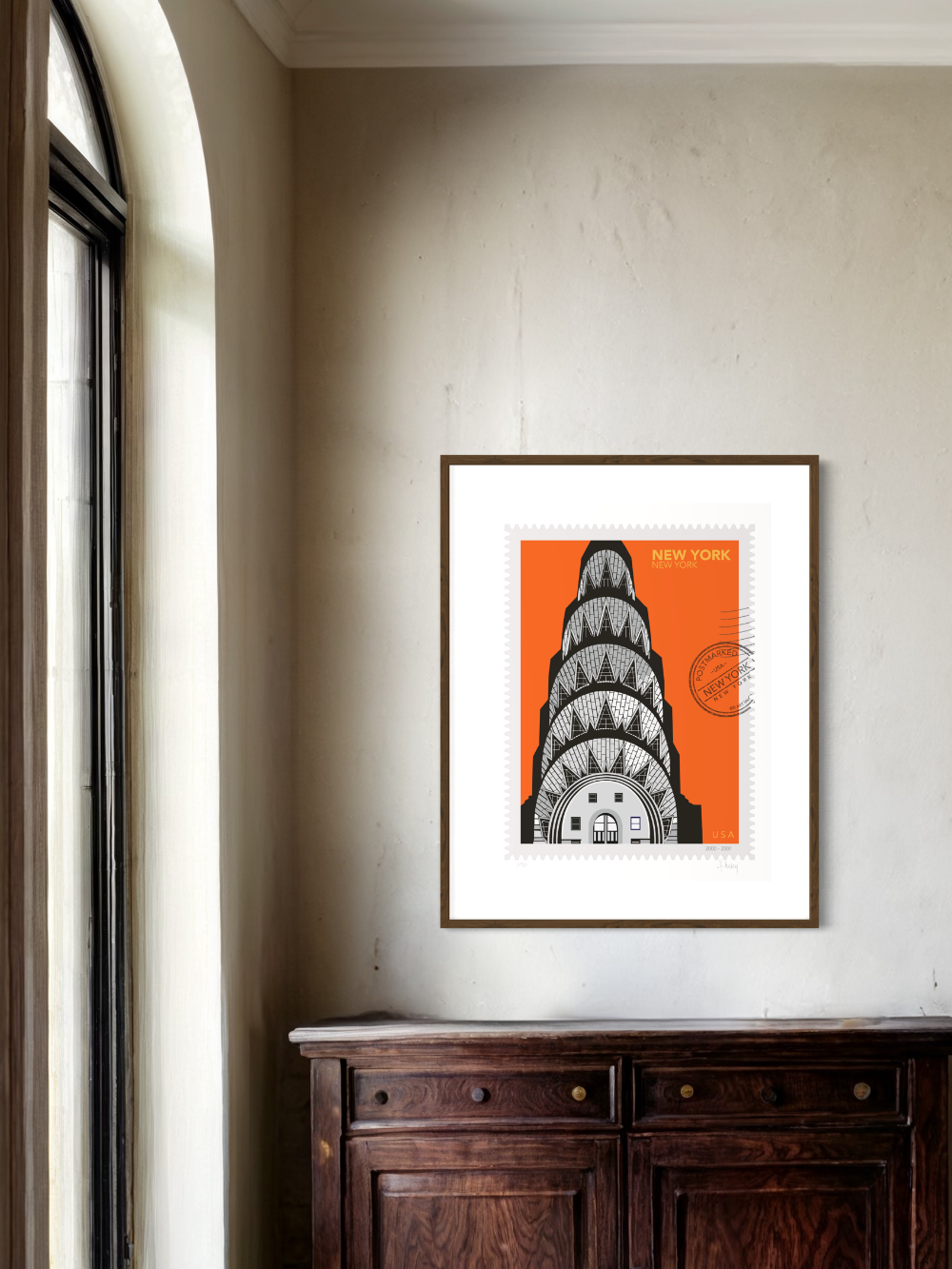 Drawing of the Chrysler Building with geometric patterns on an orange background, in a large size, New York oversized postage stamp. Framed on the white wall. Ana Hussey art.